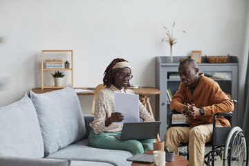 Portrait of African-American couple with handicapped man working from home together in modern interior, copy space