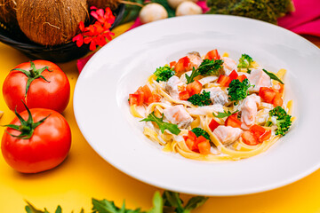 spaghetti with salmon, broccoli and tomatoes in a creamy sauce on a decorated table
