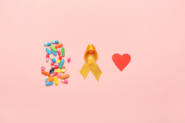 Golden ribbon, red heart and pills on color background. Childhood cancer awareness concept