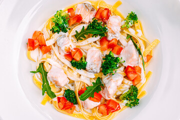 spaghetti with salmon, broccoli and tomatoes in a creamy sauce on a decorated table