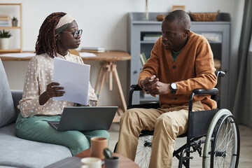 Portrait of African-American couple with handicapped man using wheelchair working from home...