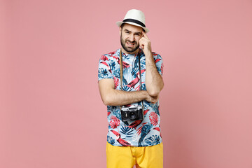 Puzzled worried young traveler tourist man in summer casual clothes hat with photo camera put hand on head isolated on pink background. Passenger traveling on weekends. Air flight journey concept.