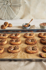 Vertical shot of chocolate cinnamon sugar rolls on a sheet pan on the table with ingredients on it