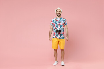 Full length of smiling young traveler tourist man in summer clothes hat with photo camera isolated...