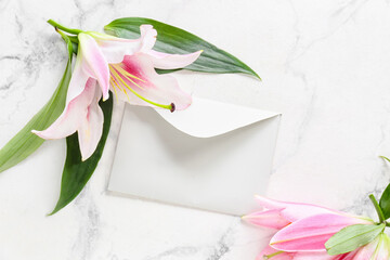 Beautiful lilies and envelope on light background