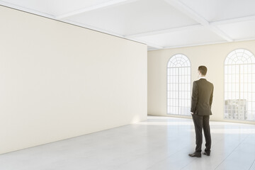 Fototapeta premium Businessman looking ion blank wall