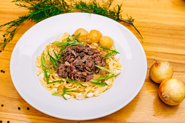 Asian national dish beshparmak with meat and baurski on a decorated table