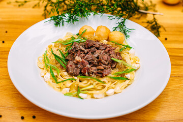Asian national dish beshparmak with meat and baurski on a decorated table