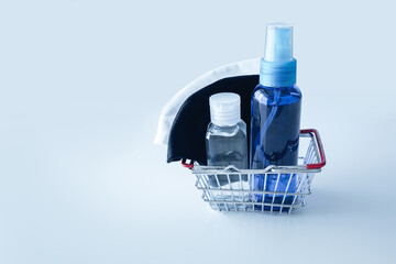 Top view of alcohol spray, alcohol gel and cotton masks in cosmetic bag for protective COVID-19, Coronavirus, new normal and next normal concept on blue background texture, Copy space for text.