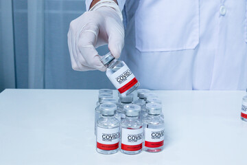 Doctor wear medical gloves hand holding vaccine bottle COVID-19 infection on blue background. Coronavirus Covid-19 vaccination concept.