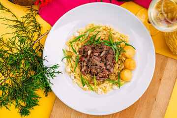 Asian national dish beshparmak with meat and baurski on a decorated table