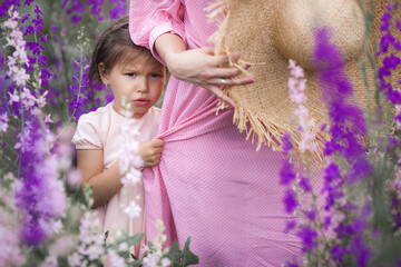 Cute little funny girl holding her mom by the dress. Shy baby