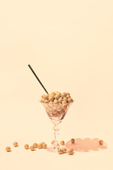 Martini glass with decorative golden balls and straw on pastel background. Festive and party concept. Minimal style.