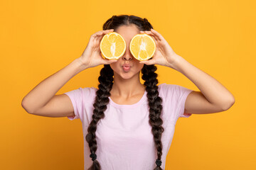 Indian lady covering eyes with halves of citrus orange fruit