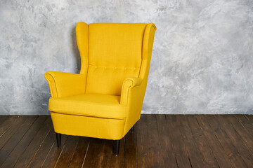The yellow textile chair stands on a dark brown wooden floor