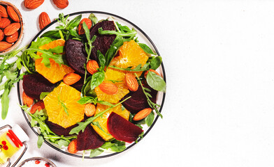Beetroot Salad with Orange, arugula and almonds nut on white background. Vegan healthy summer food. Top view. Copy space