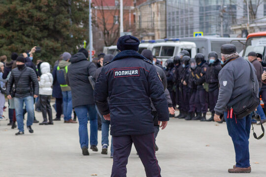 Police officer watching man's arrest. Opposition activists protest in Russia, Krasnodar, 2021, to support Alexei Navalny, against outrage.