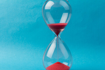Crystal hourglass on blue background as a concept of passing time for business term, urgency and...