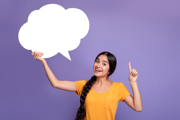 Smiling indian woman pointing finger up hoding speech bubble