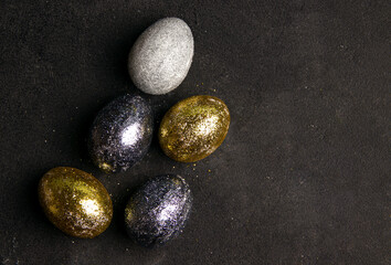 Easter concept in modern style. Eggs in sparkles on a black background. Copy space.