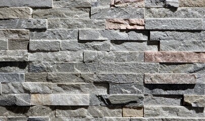Cladding wall made of small uneven stone bricks, predominantly gray. Background and texture.