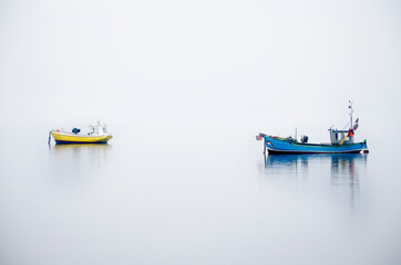 Szerokie minimalistyczne ujęcie kutrów rybackich na Zatoce Gdańskiej podczas zamglonego poranka