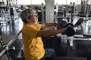 FIt old man lift dumbbell and stretch arms in gym