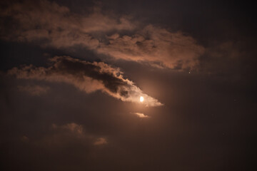 Naklejka na ściany i meble first quarter moon on the night sky seen trough brightly clouds during summer season