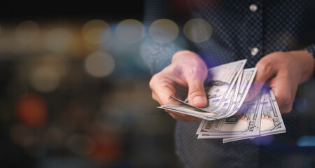 The hand of a business woman counting dollar bills, copy space, black background, money saving...