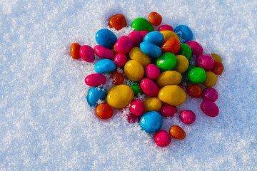 Multicolored candies, dragee in the snow. Sweets in the snow. Valentine's Day. Sweets as a gift....