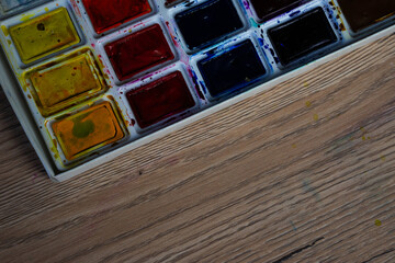 Watercolor paints on a wooden table. Paints background.