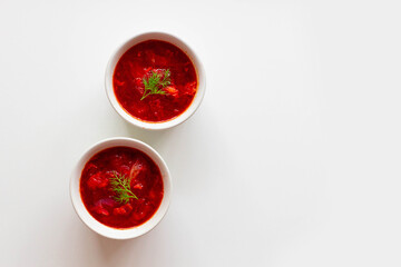 Homemade Traditional Ukrainian beet soup with fresh green dill. Russian borscht in bowl of tomatoes on white background