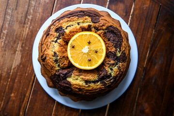 Homemade chocolat-orange cake decorated with orange slice on a dark wood background.