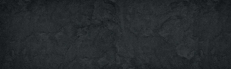 Black rough concrete wall wide texture. Fine textured cement plaster. Dark gray grunge widescreen...