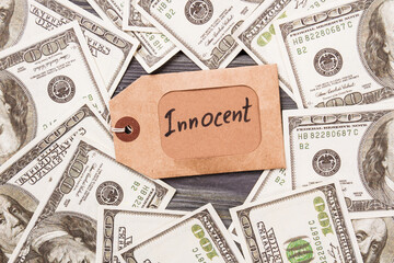 Label with innocent word. Pile of us dollars.