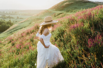 Young beautiful woman in boho style dress and hat on nature at sunset. © Oksana