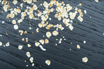 Dry oat flakes on a dark background close-up, top view. Background of dry oatmeal
