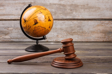 Brown globe with gavel on wood. International court concept.