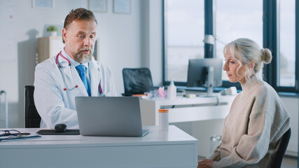 Fototapeta premium Friendly and Cheerful Family Doctor is Prescribing Tablets and Vitamins to Senior Female Patient During Consultation in a Health Clinic Office. Physician Giving Medical Urine Specimen Container.