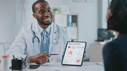 Doctor Consultation Office: Female Patient Listens to Experienced Cardiologist Uses Digital Tablet Computer to Show, Explain Heart Analysis Results, Give Advice, Prescribe High-Pressure Medicine
