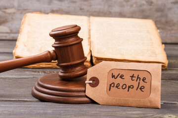 Trial and justice concept. Wooden gavel with law book and we the people slogan.