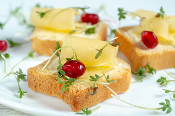 Mini toast with butter, cheese and watercress micro greens on a white plate. Breakfast concept, Macro and blur.