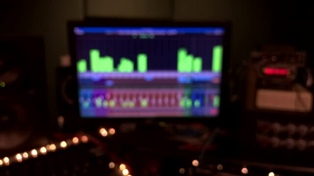 A dark and blurred sound recording studio type background with moving level meters and flickering led lights