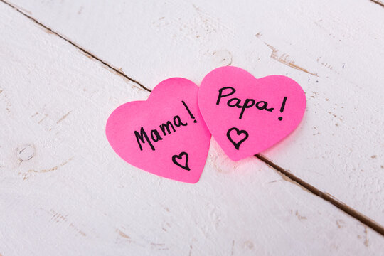 Pink hearts with mama and papa text on wooden background