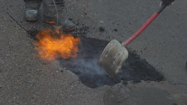 Utility Workers Fixing Gap in a Road by FIlling it with Hot Asphalt