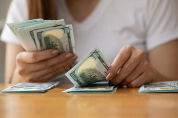 Woman counting American money or 100 USD dollars note  at table,finances, accounting and business concept 