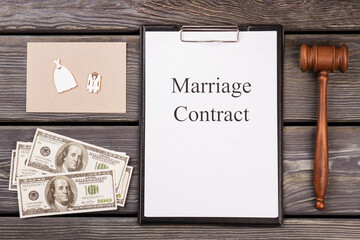 Flat lay marriage contract with money and gavel. Brown gavel with dollars. Wooden desk background.
