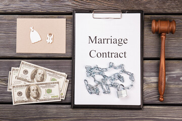 Marriage contract with chains. Fake marriage concept. Wooden gavel with money and wedding costumes.