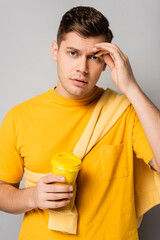 Man looking at camera while holding takeaway drink on grey background