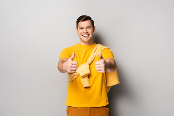 Smiling man showing thumbs up on grey background